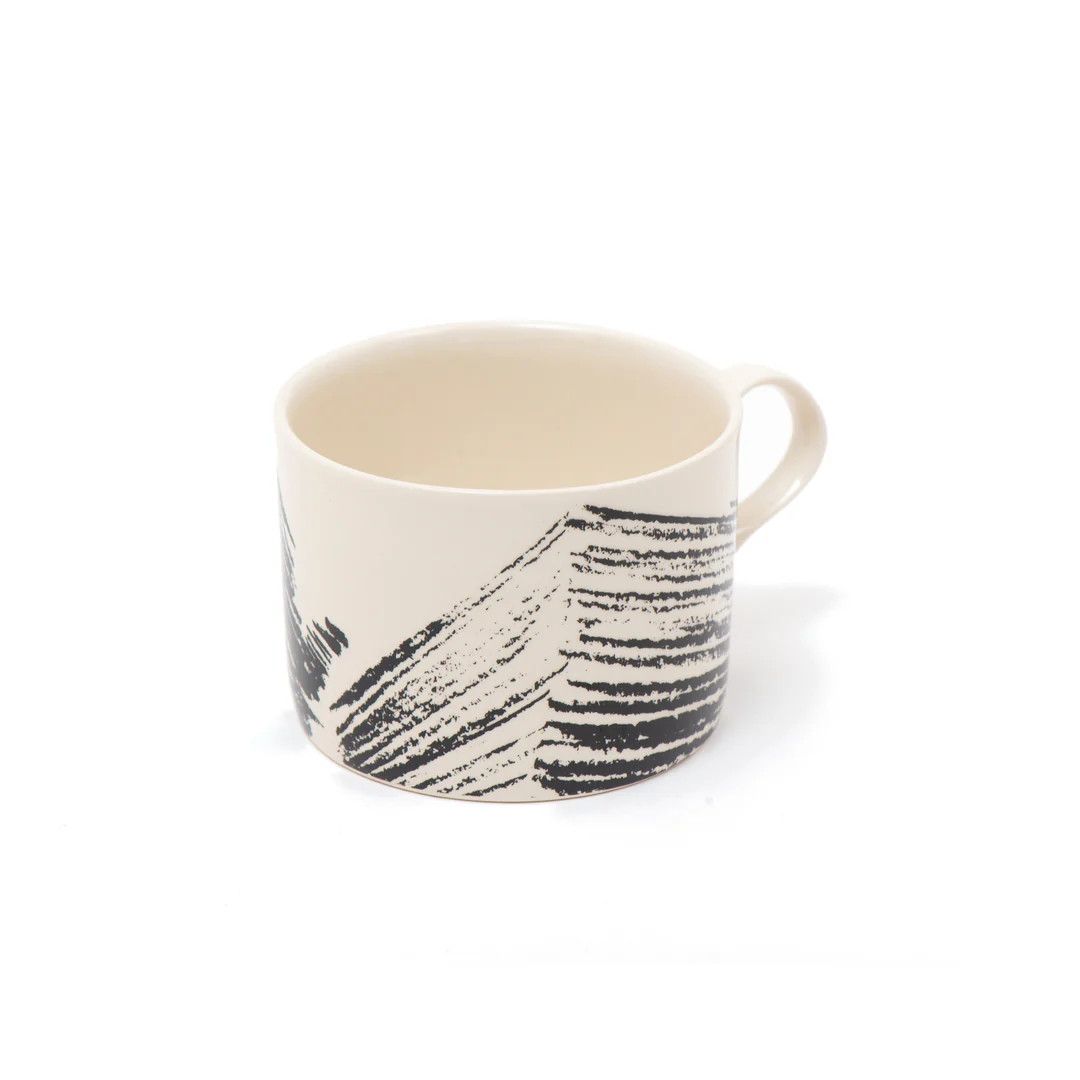 A ceramic mug with a black design on it.