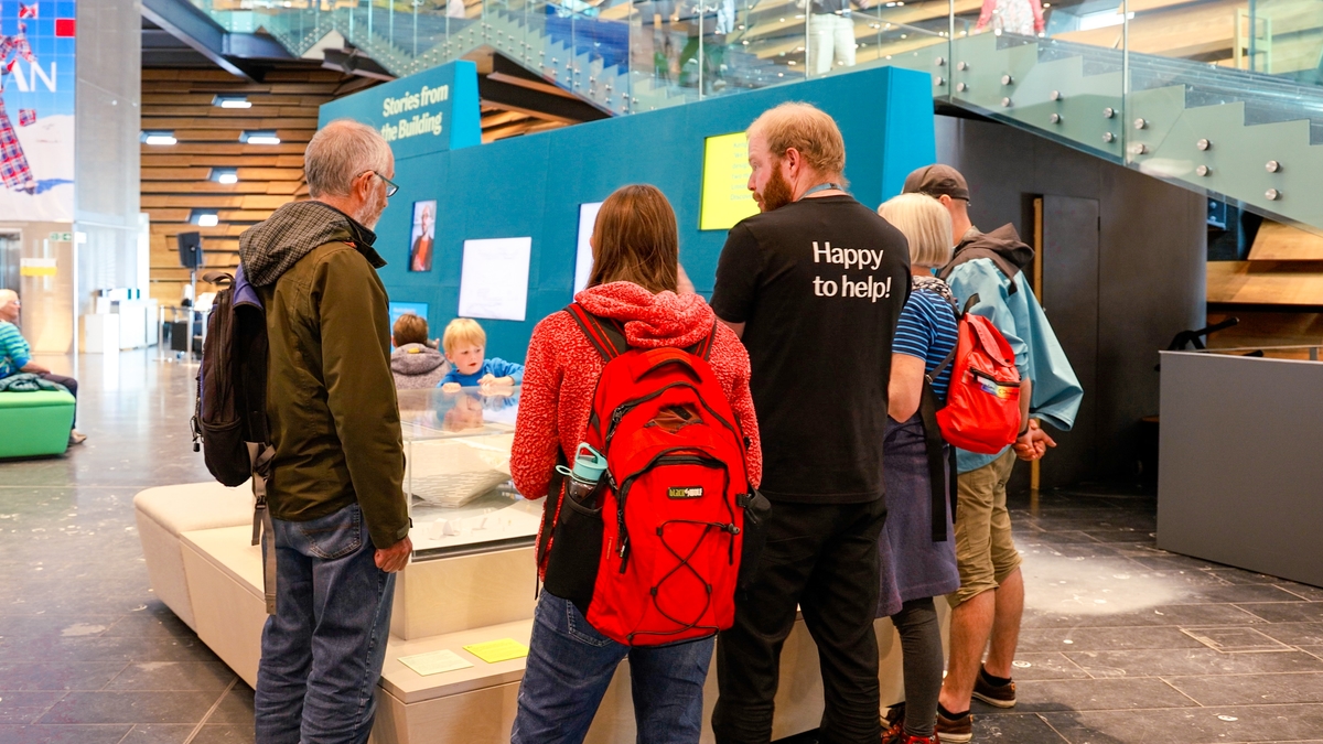 A group of visitors on a tour of the museum given by a visitor assistant
