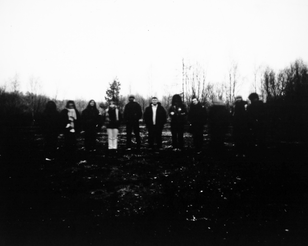 A black and white image of people standing in a field.
