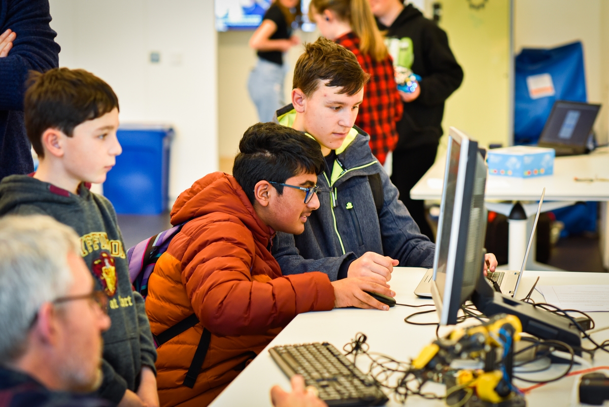 Three young boys operating a hobby robot using a computer at V&A Dundee