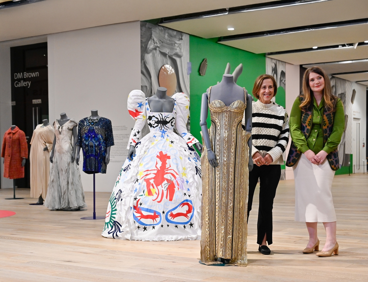 Two people posing next to mannequins.