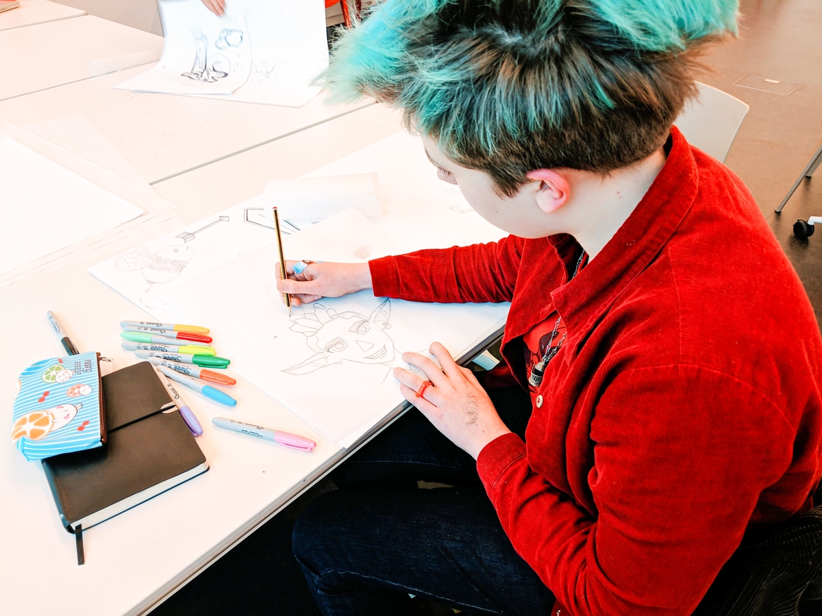 A young person sketching on a piece of paper