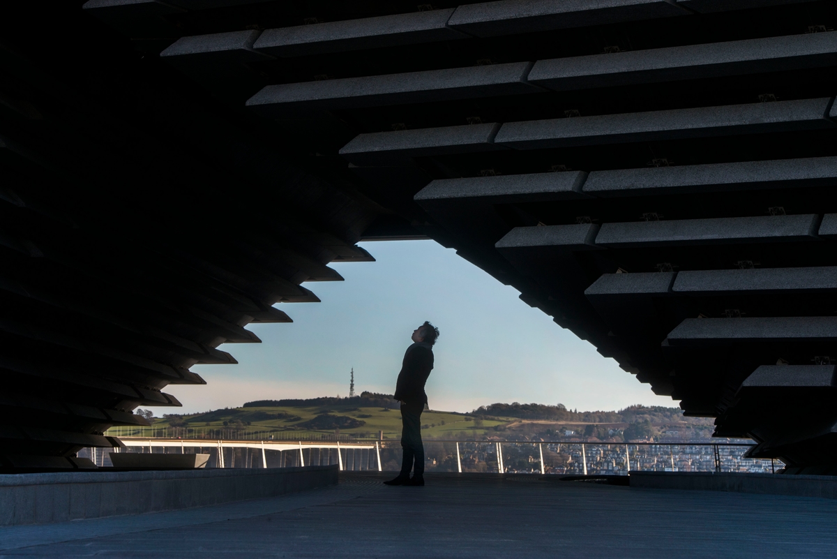 A man standing under the arch at V&A Dundee