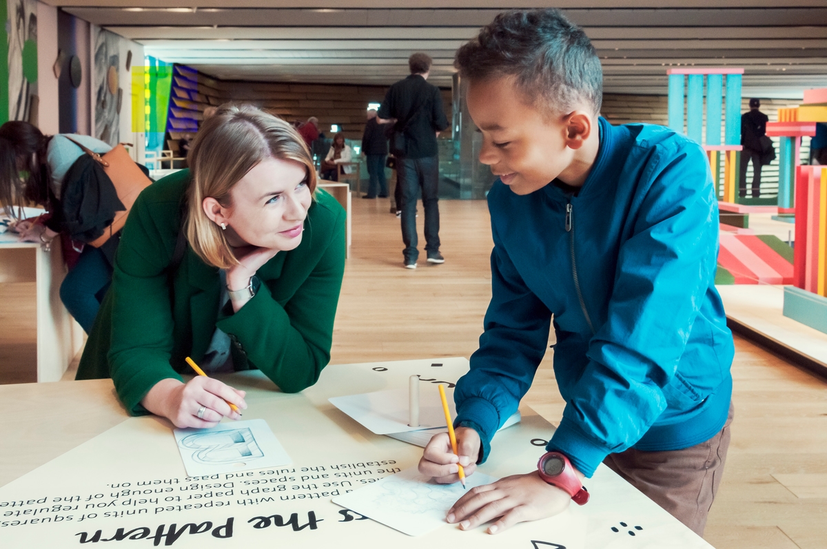 Two visitors engaging in an activity in the foyer of V&A Dundee