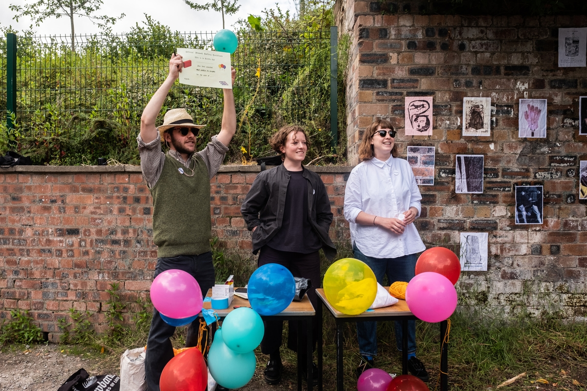 The people from Wooosh Gallery standing by a table covered with balloons