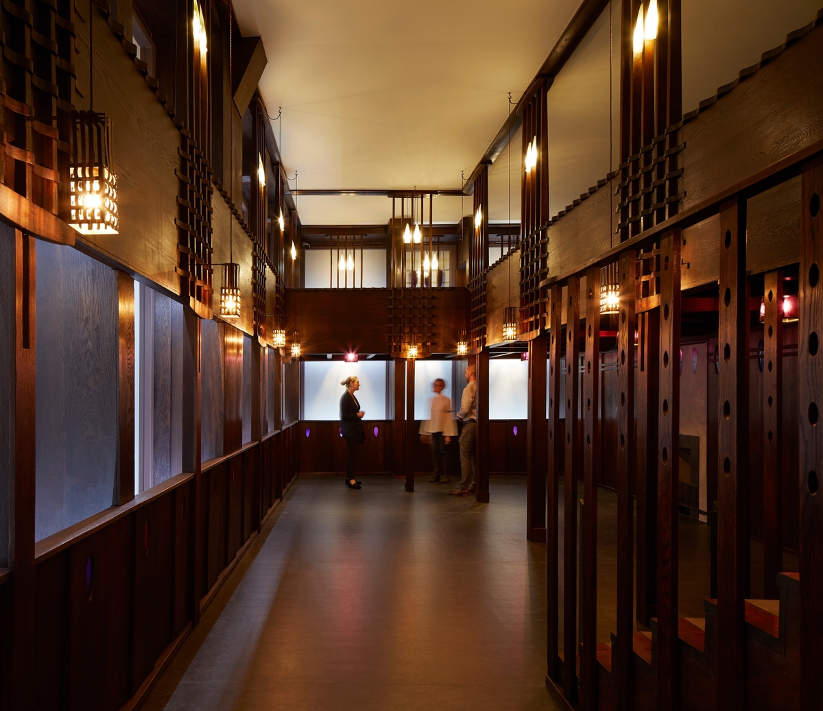 A visitor assistant speaking with two visitors in the Rennie Mackintosh Oak Room