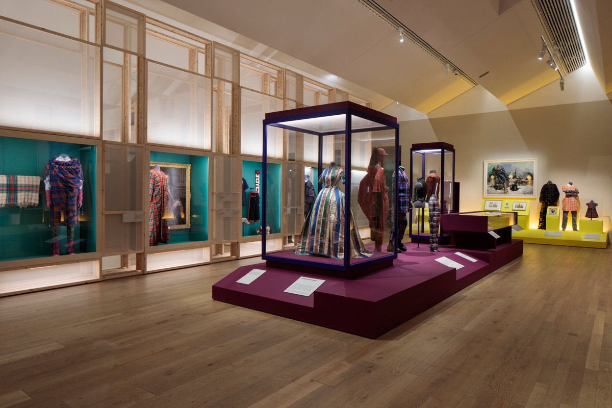 A collection of display cases featuring tartan fashion pieces, including dresses, jumpsuits and shawls.