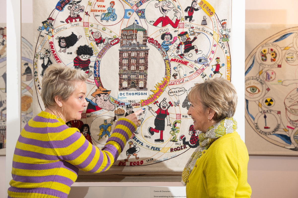 Two women looking at a panel in the Dundee Tapestry exhibition at V&A Dundee