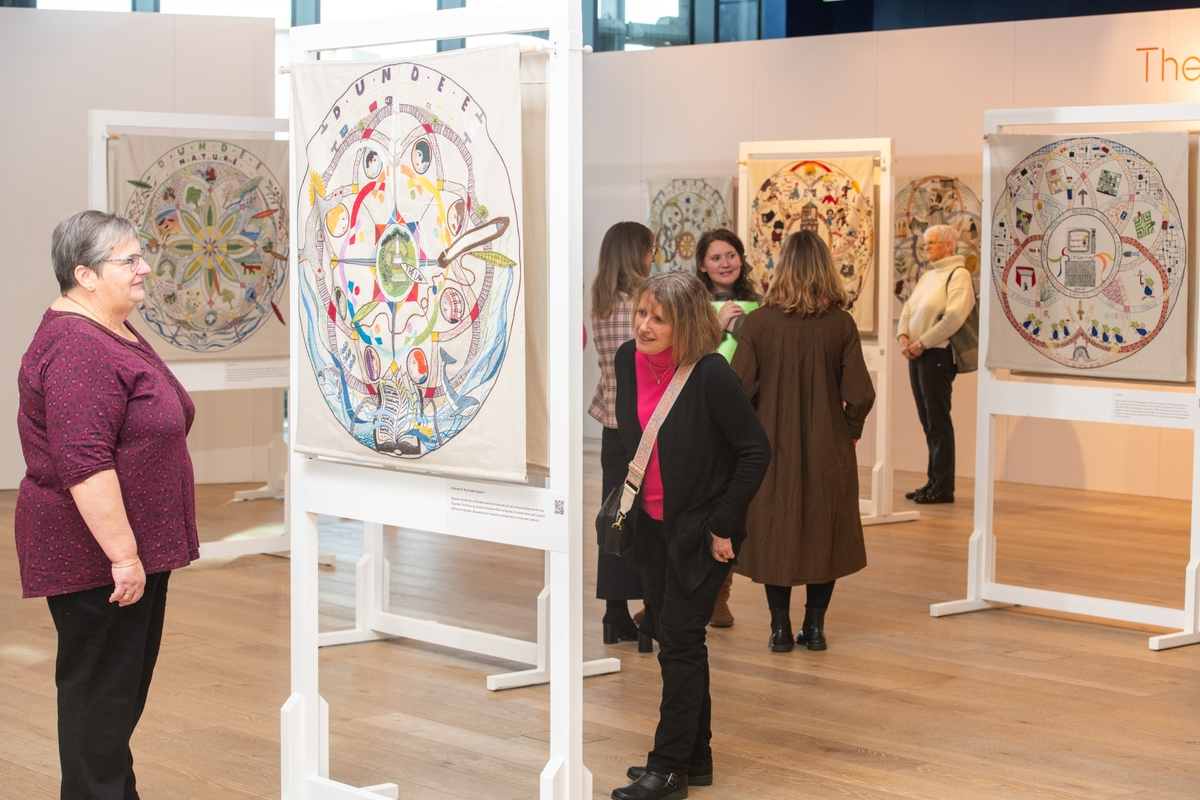 A group of visitors looking at the Dundee Tapestry panels on display at V&A Dundee