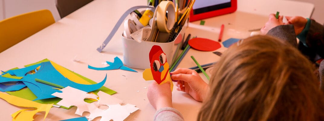 A photo of a child making a character out of pieces of coloured paper