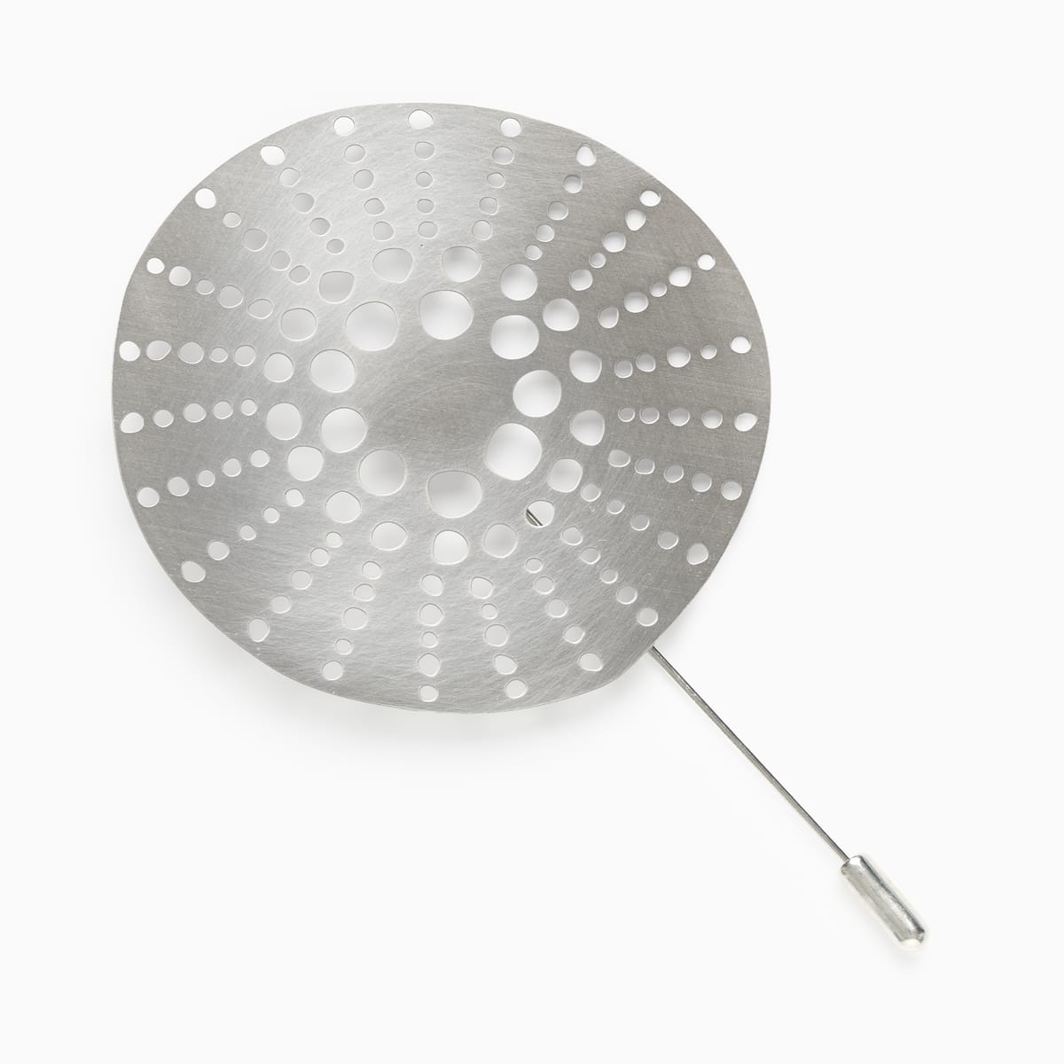 A silver brooch which is round with lots of holes pierced through the metrical in a circular design.