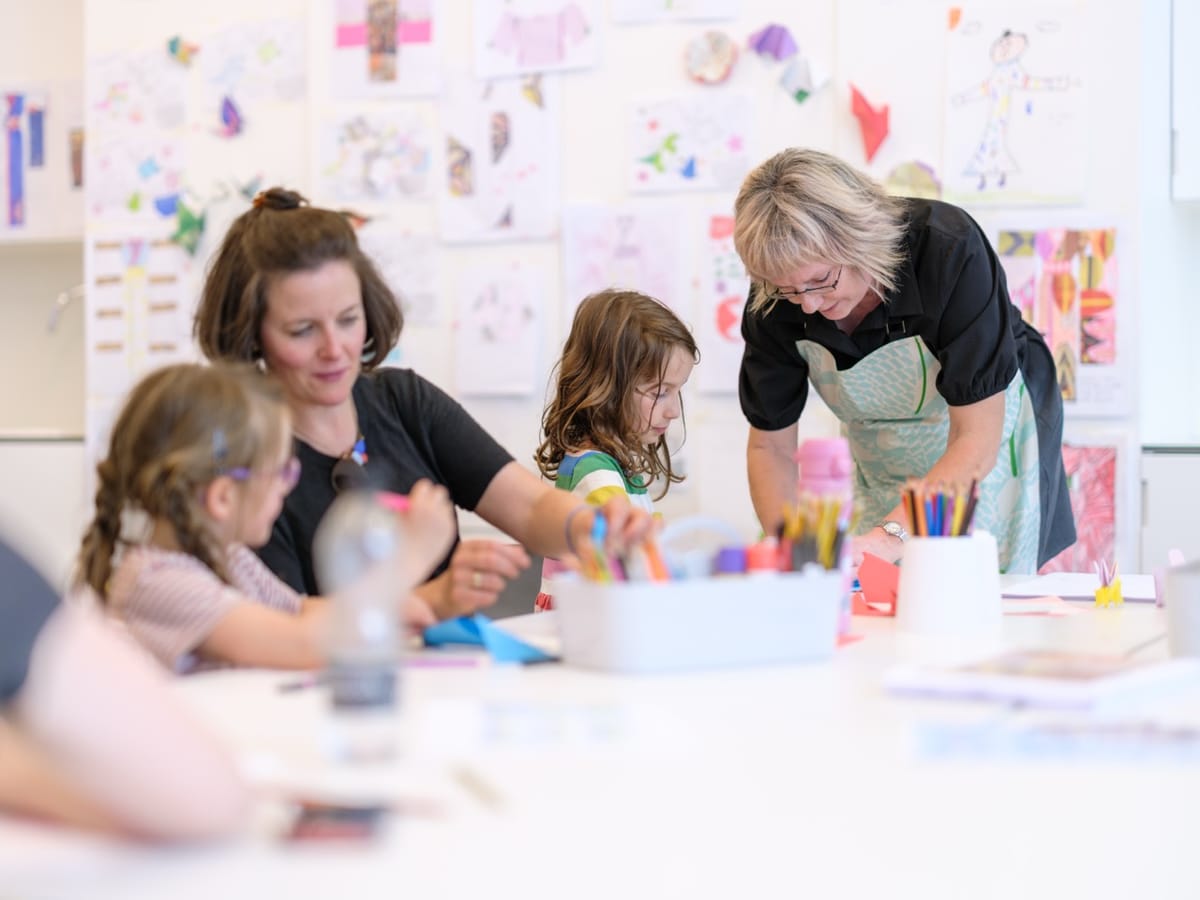 A group of people crafting things on a table with pens and pencils.