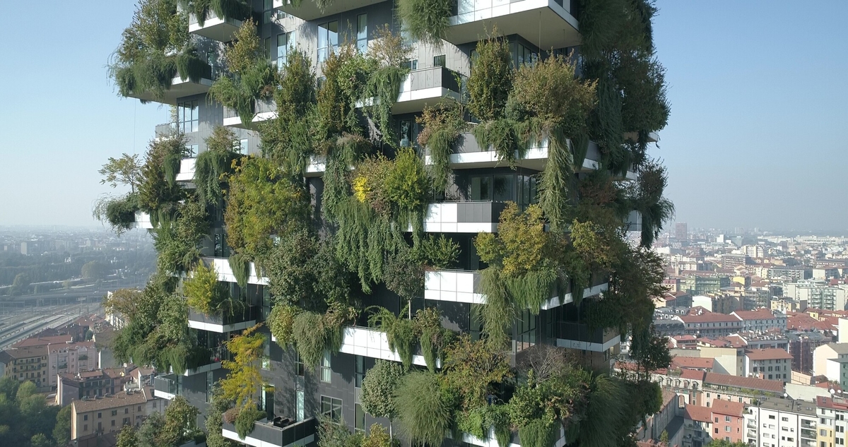 A modern high rise building with balconies in different sizes and each balcony is covered in green plants.