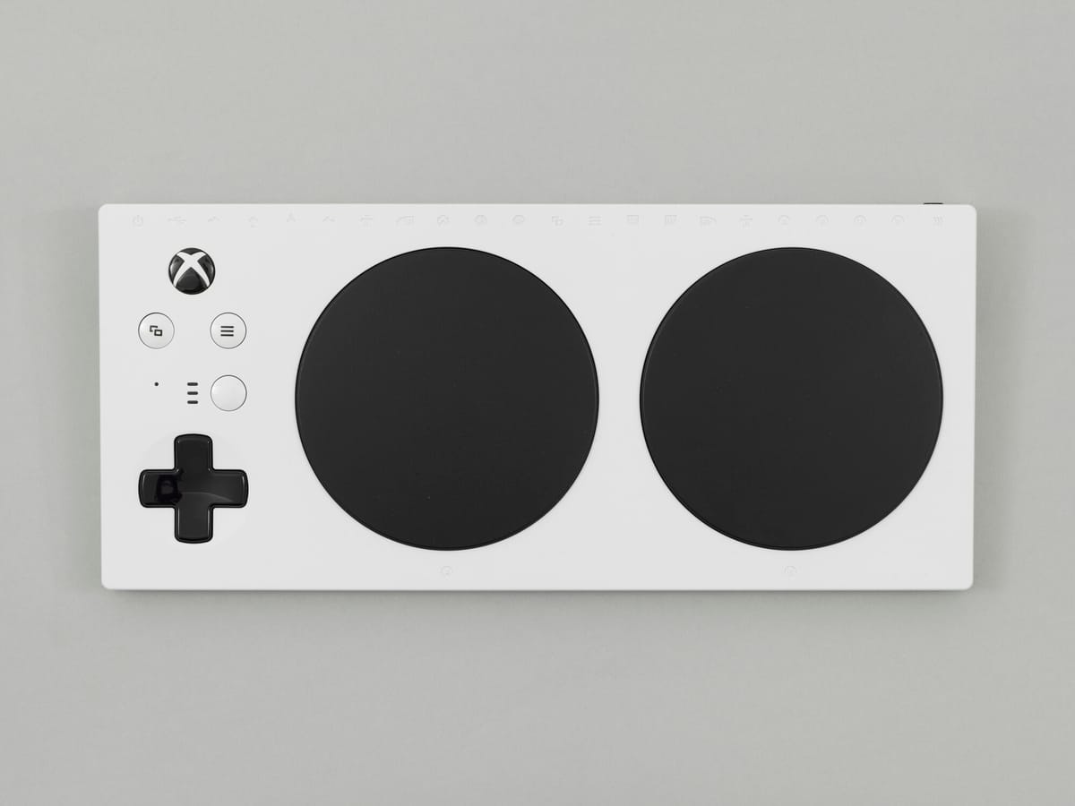 White adaptive gaming controller with large black buttons and d-pad on a gray background, designed for accessibility.