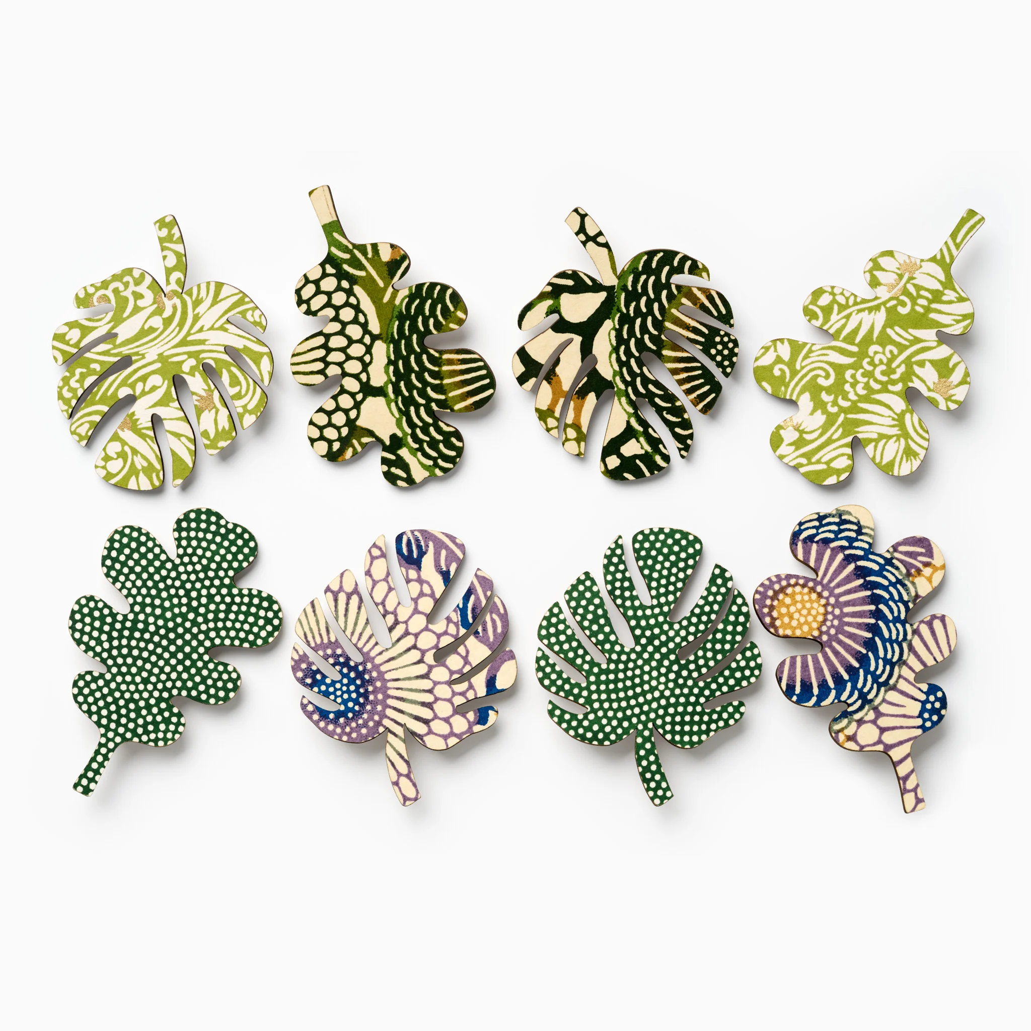 eight green leaf brooches sitting alongside each other in a row
