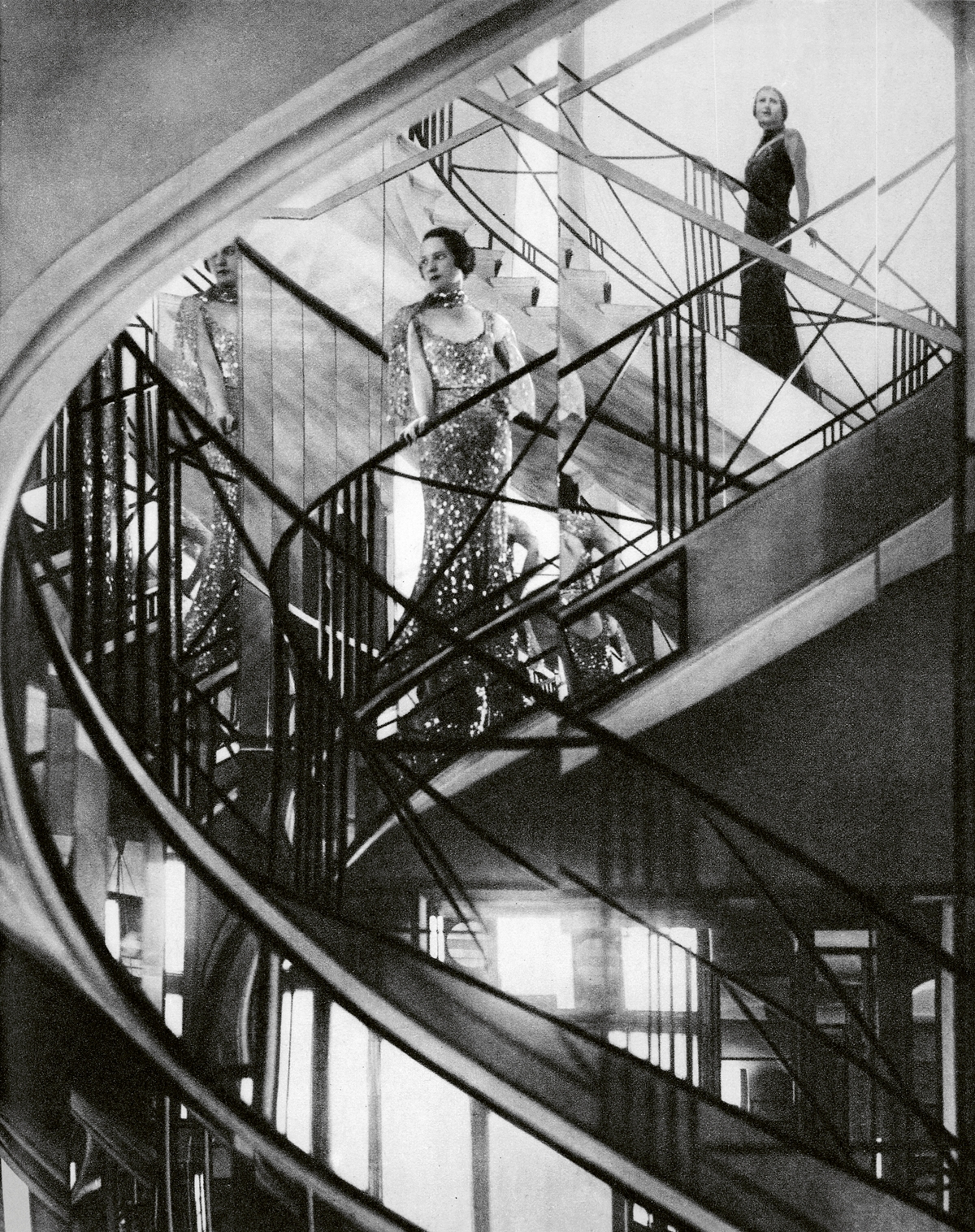 A black and white image of a woman standing on a mirrored staircase.