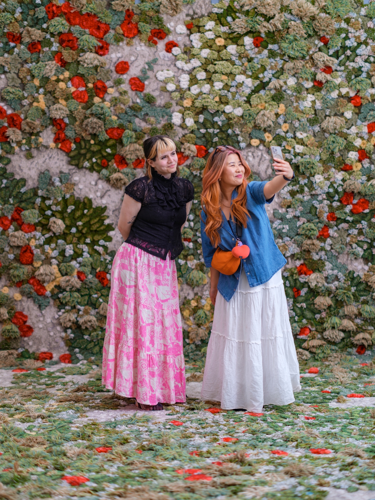 Two people standing taking a photo of themselves standing on a floral meadow.